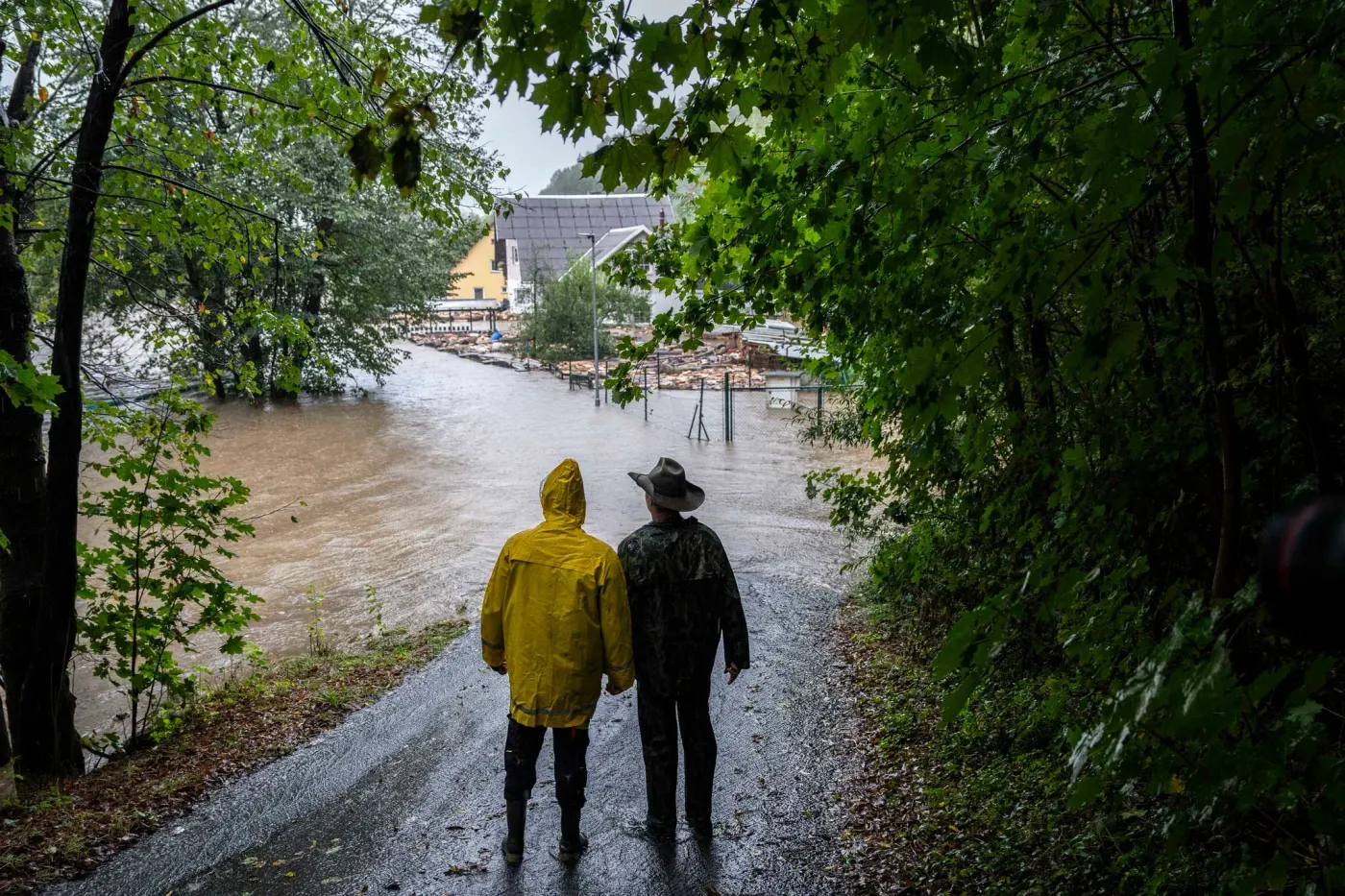Dva lidé stojí na cestě a dívají se na zaplavenou ulici