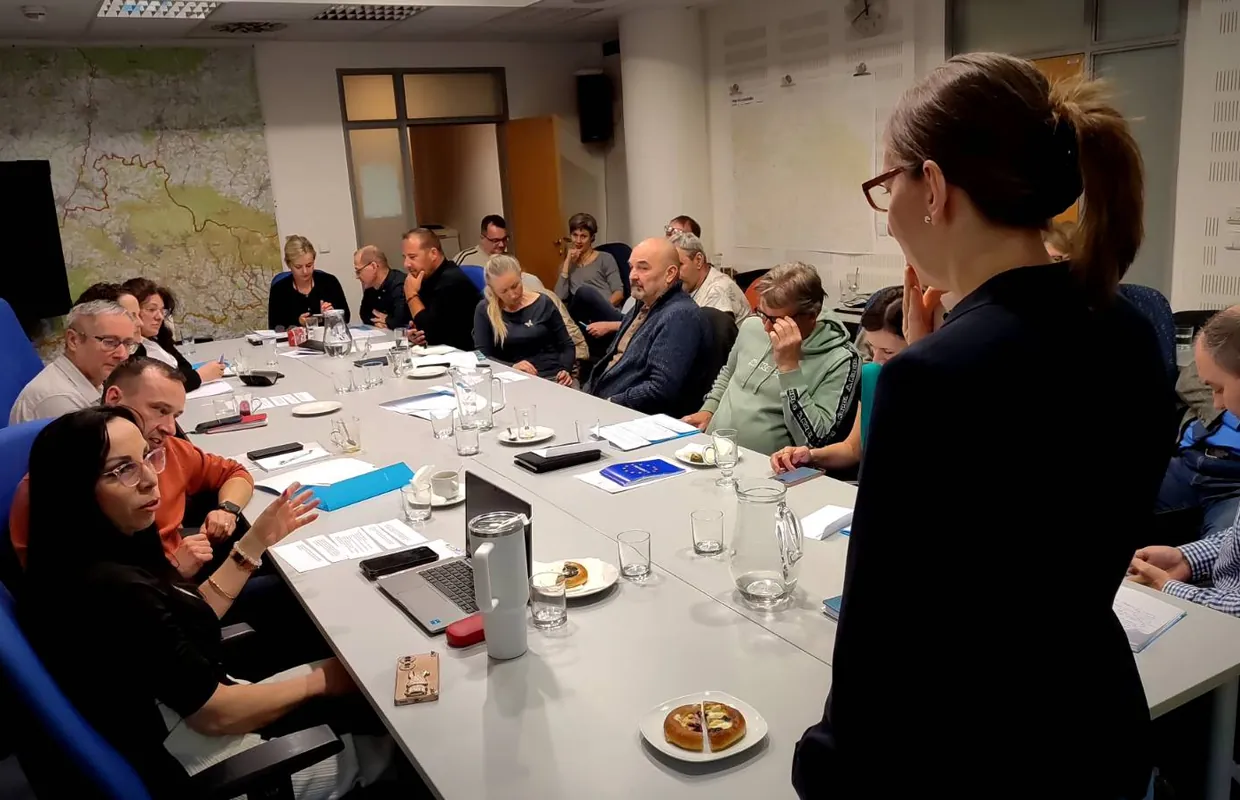 Školení Akademie akutní komunikace: lektorka stojí u stolu s účastníky
